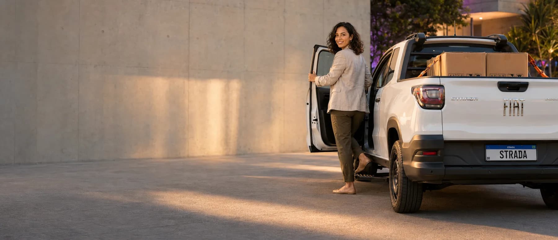 Mulher entrando em uma Fiat Strada ao entardecer